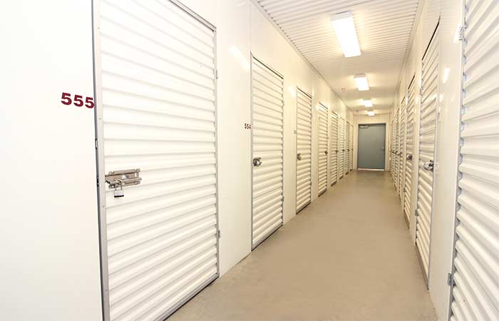 Indoor climate controlled storage units in a well-lit hallway with swing doors.