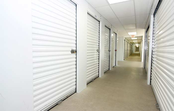Indoor climate controlled storage units with roll-up doors in a well-lit hallway.