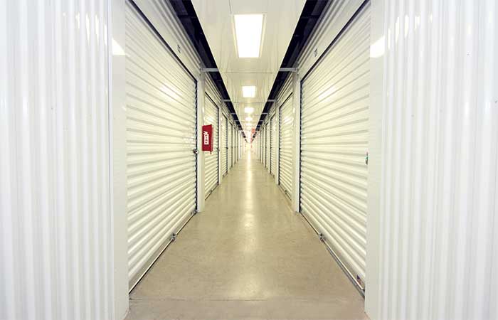 Indoor climate controlled storage units with roll-up doors in a well-lit hallway.