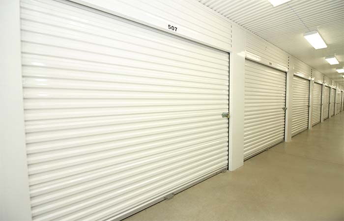 Large, indoor, climate controlled storage units in a well-lit hallway.